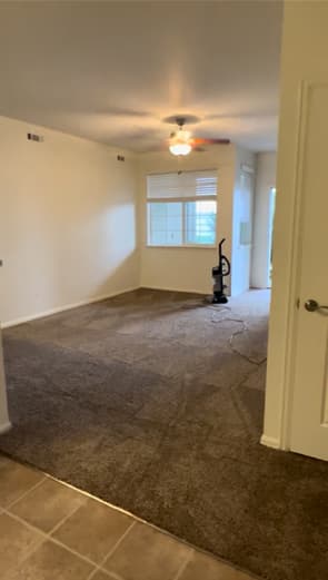 Freshly finished brown carpet with vacuum tracks meeting beige tile