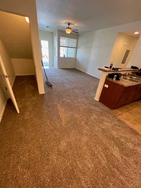 Plush brown carpet in a living area meeting tile at the kitchen
